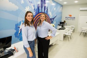 Duas funcionárias sorrindo para a foto dentro de uma agência Flytour.